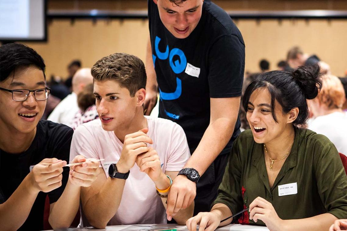 Four students at a table, engaging with one another.
